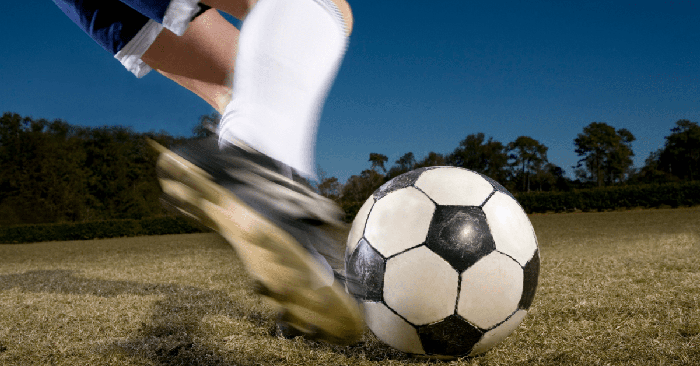 person kicking soccer ball