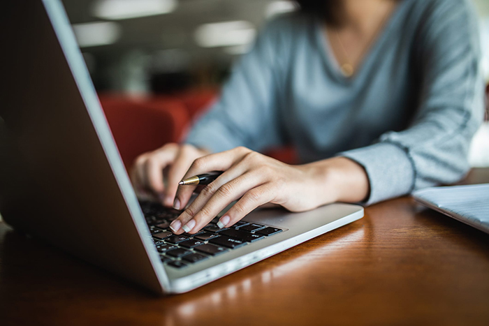 a woman's hands type on a laptop