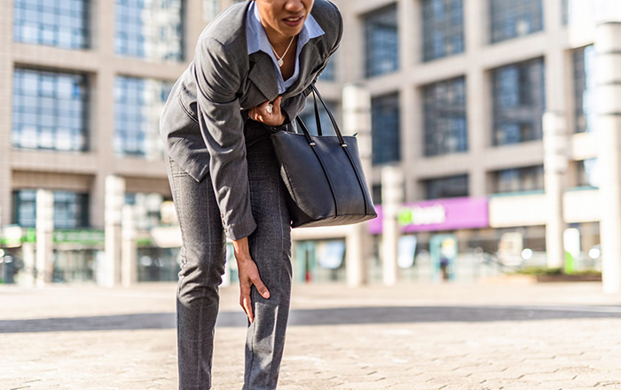 Business woman bending over holding her knee