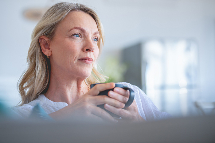 Woman sit on couch while holding a mug