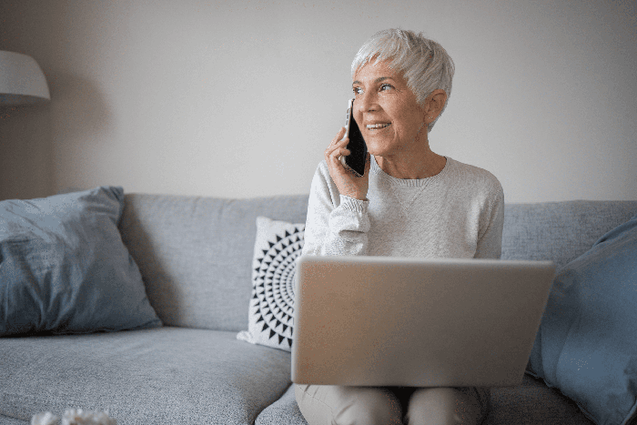 senior woman using a laptop and a phone