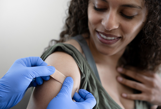doctor places bandage on arm of patient after vaccine