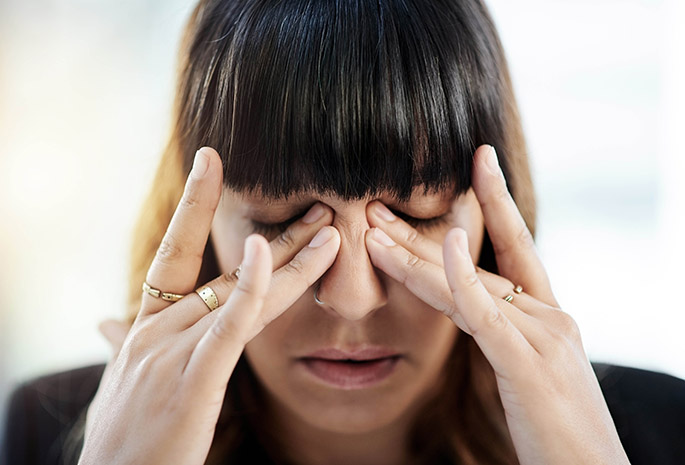 woman rubs under her eyes while experiencing concussion symptoms