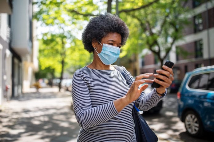 woman with mask on scrolling her phone