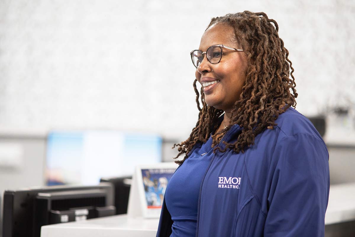 RN in scrubs smiling at nurses’ station.