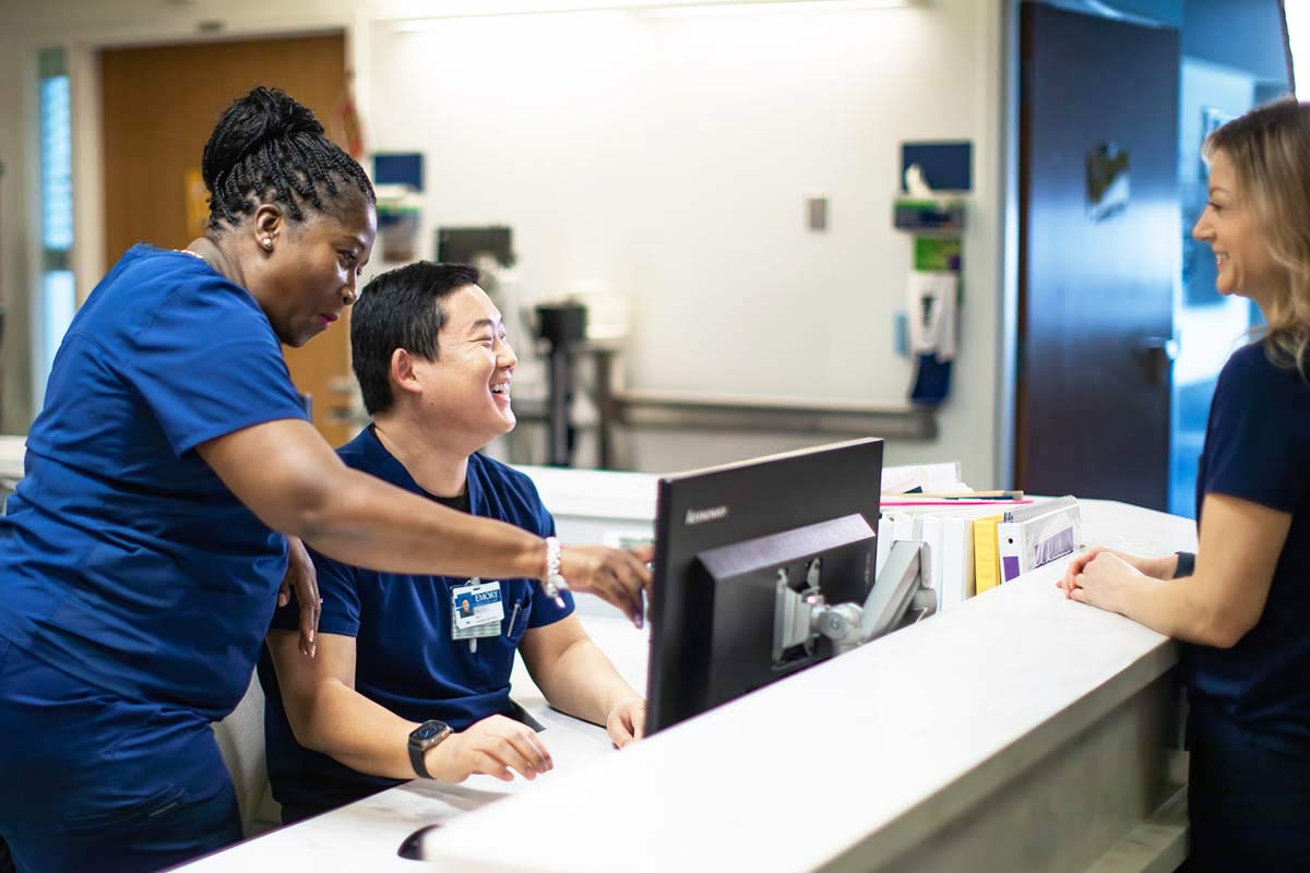 Nurses in scrubs gathered at front desk.