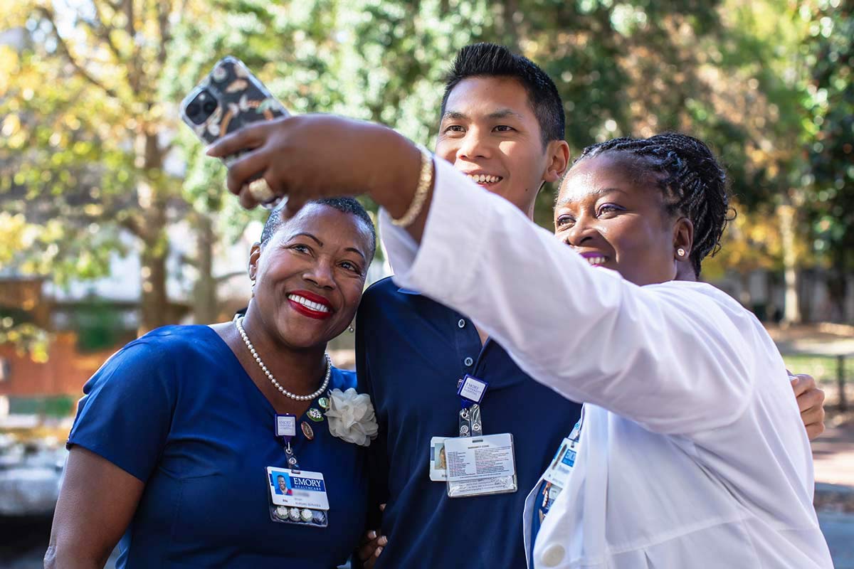 Group of nurses smiling and taking selfies outside the hospital.