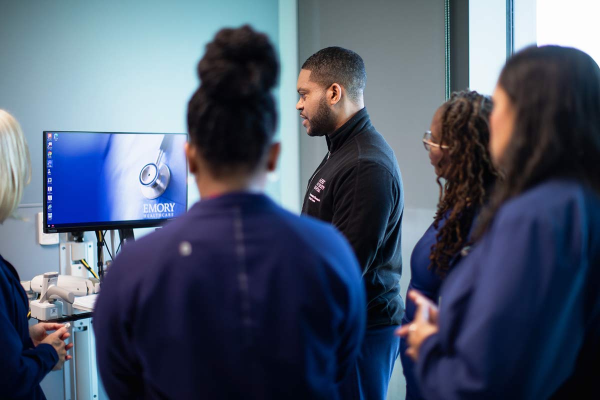 Nurses in scrubs discussing patient care in room.