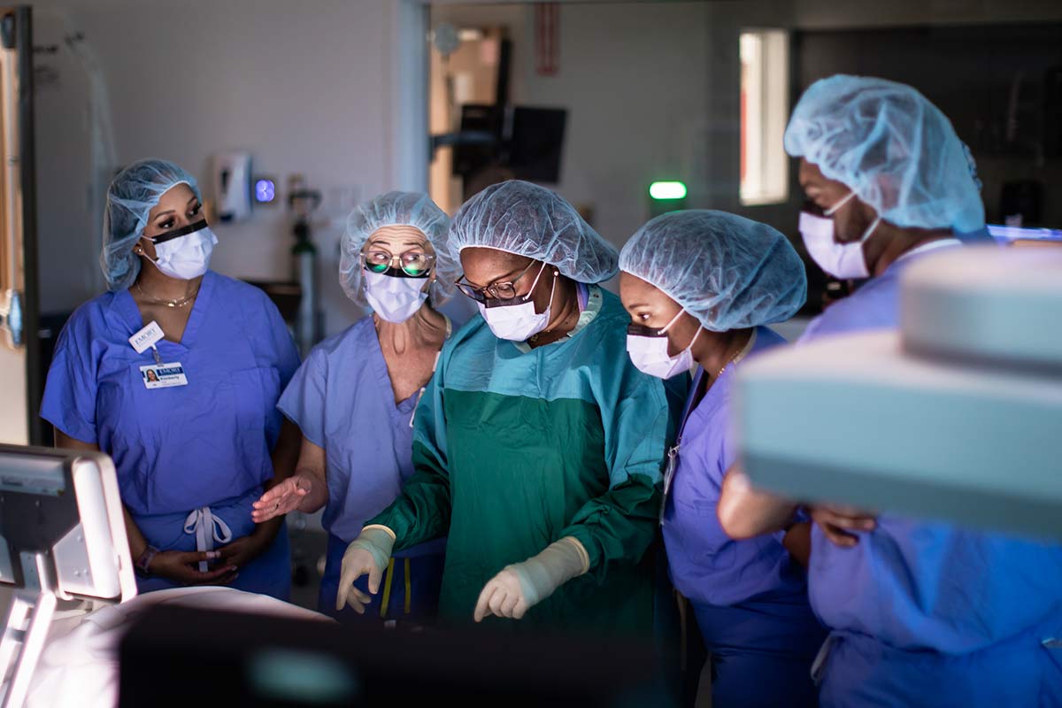 Group of nurses in scrubs discussing protocols in OR room.