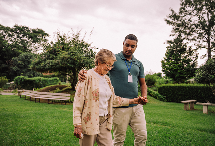 community health worker walking with elderly woman