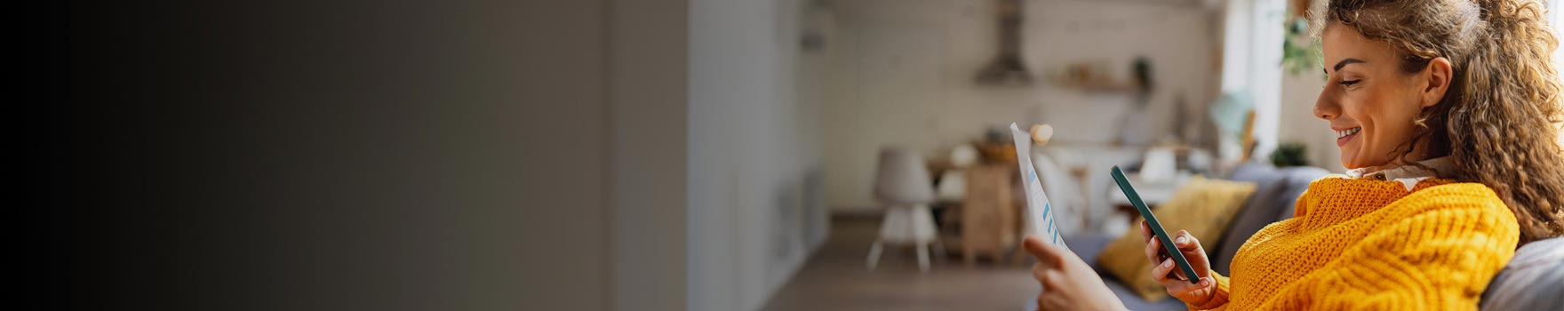Woman sitting on a sofa looking at her phone and smiling