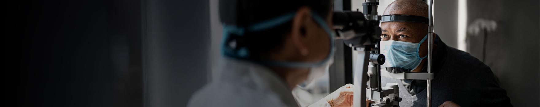man wearing a mask undergoing eye exam at machine