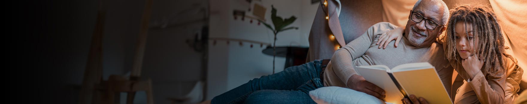 elderly man reading to small child in kid's bedroom