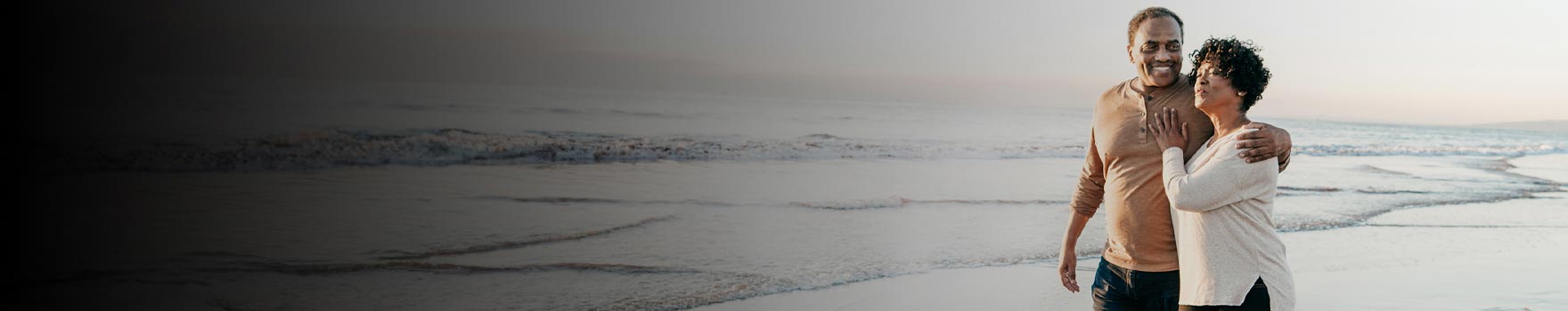 Older couple walking on the beach on a sunny day