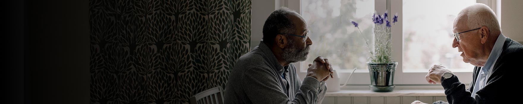 two men in serious conversation by the kitchen window