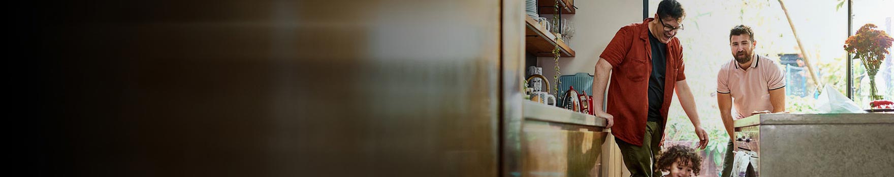 older man and younger man look on as toddler plays in front of them