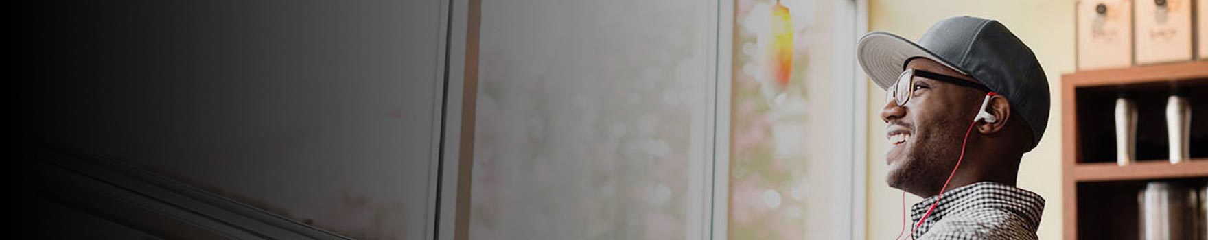 man smiling while listening to ear phones and looking out of the window