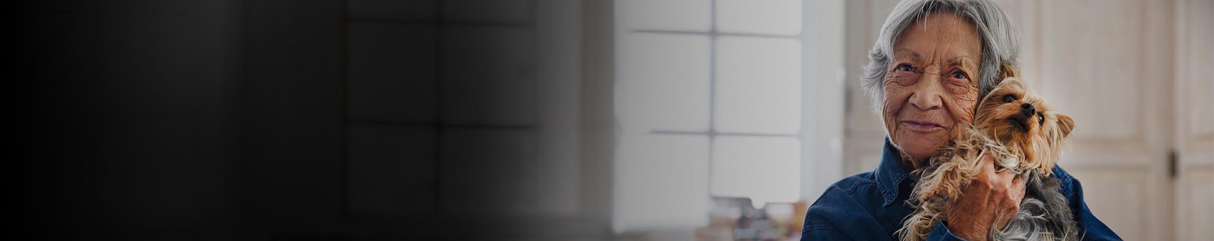 elderly woman holds small puppy close to her face