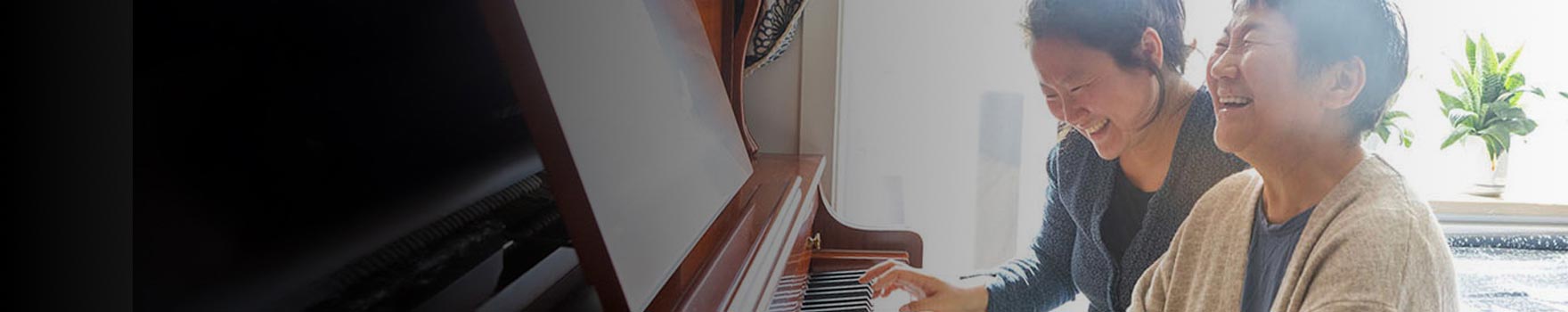 two women playing the piano together and laughing