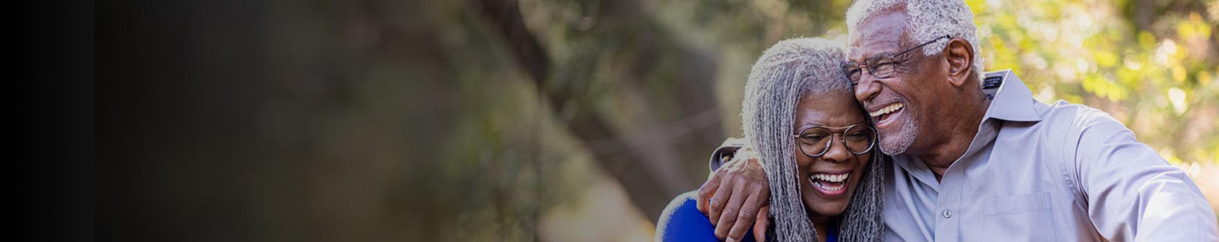 elderly man holding woman close to him as both of them laugh