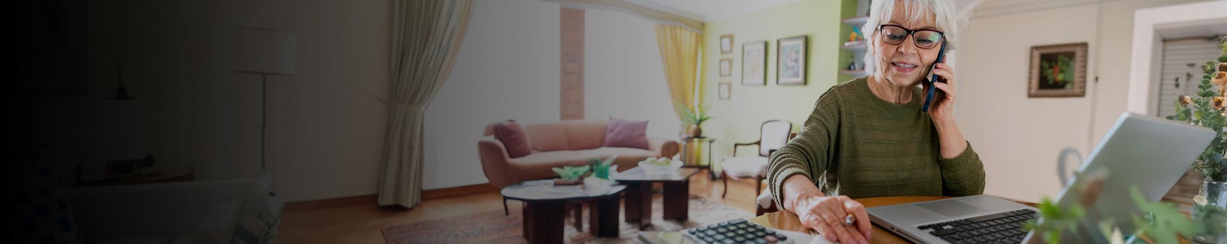 Woman multitasking with her phone pressed to her ear and laptop open