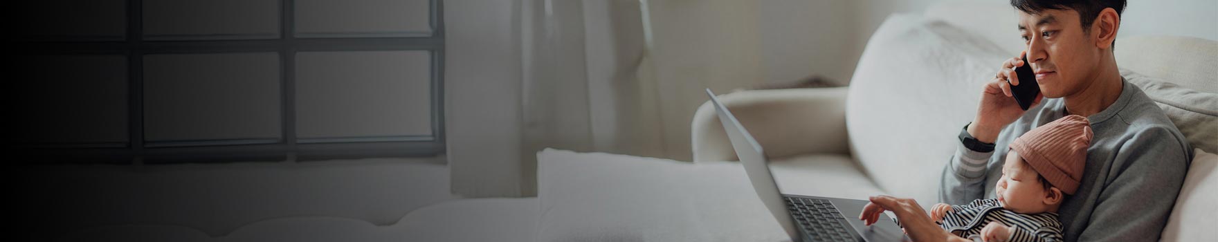 A father on the phone and holding a new born baby