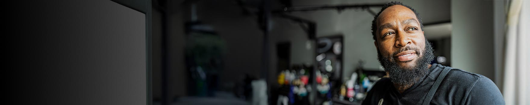 A man in his 30s looking outdoors and smiling