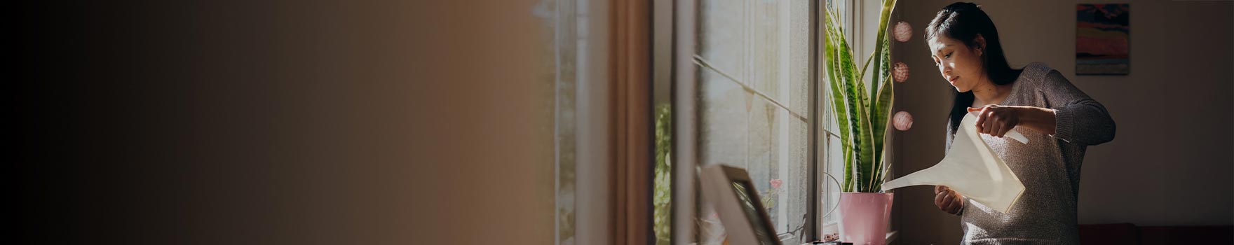 A younger woman watering her indoor plants