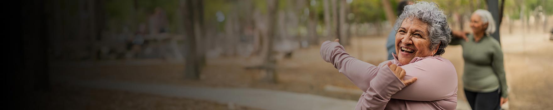 An older woman on an outdoor group setting stretching and getting ready for a workout