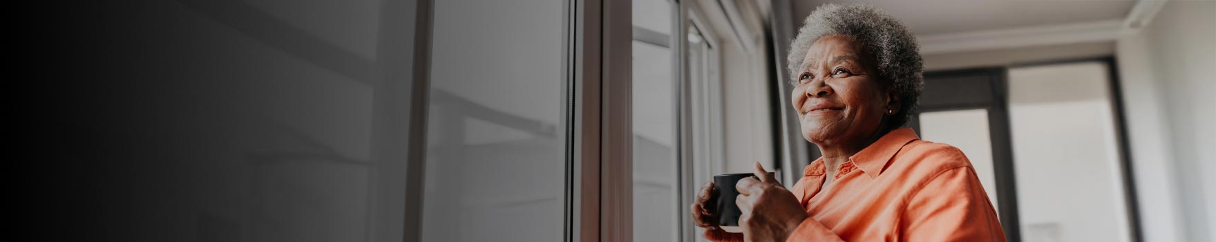 An older woman drinking a warm cup of coffee
