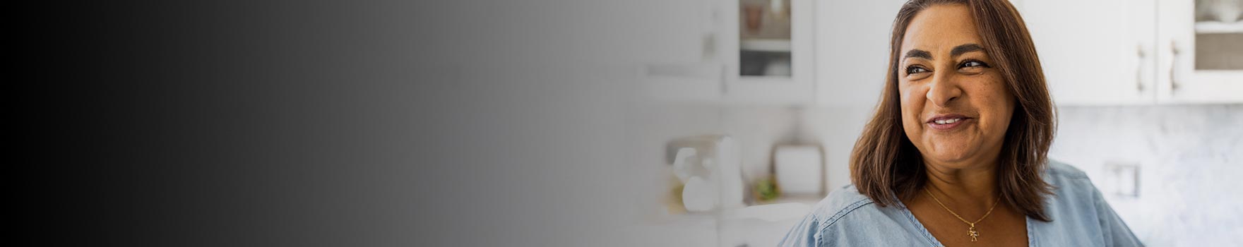 A woman in her early 50s smiling in a kitchen