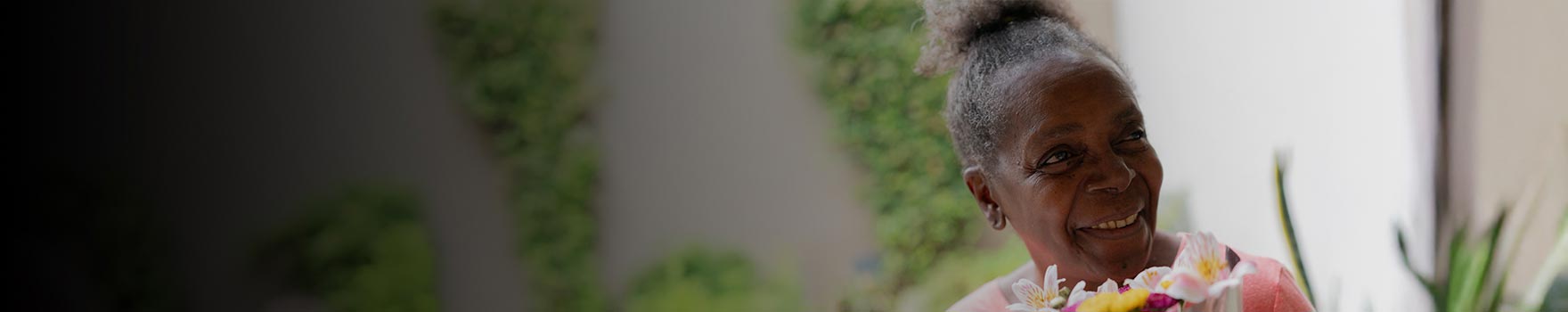 An older black woman holding flowers