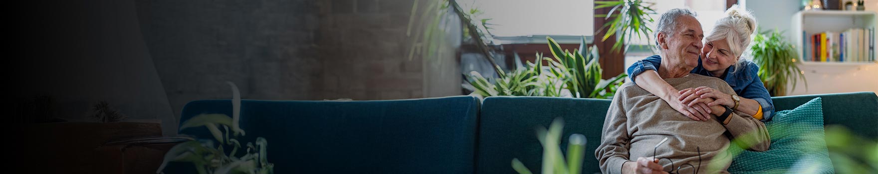 An older couple inside their home hugging and smiling 