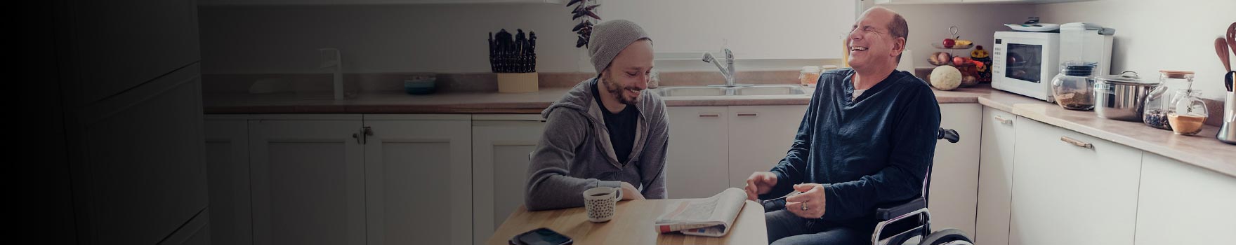 Two men inside a kitchen laughing together