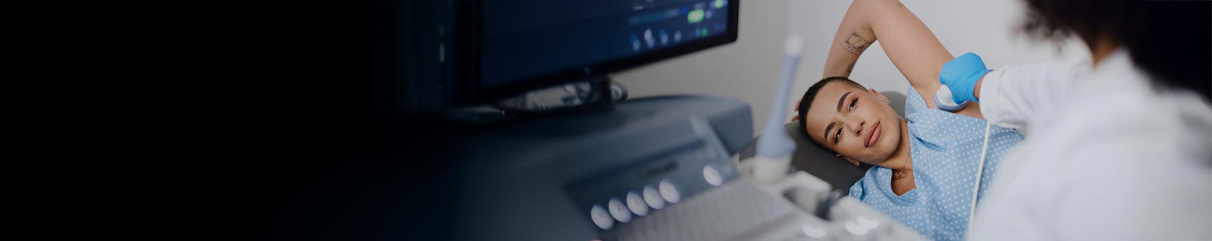 woman lying on exam table while technician scans under her arm