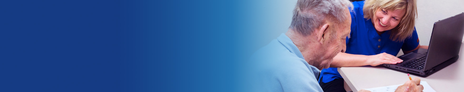 man doing a worksheet beside a woman on a laptop