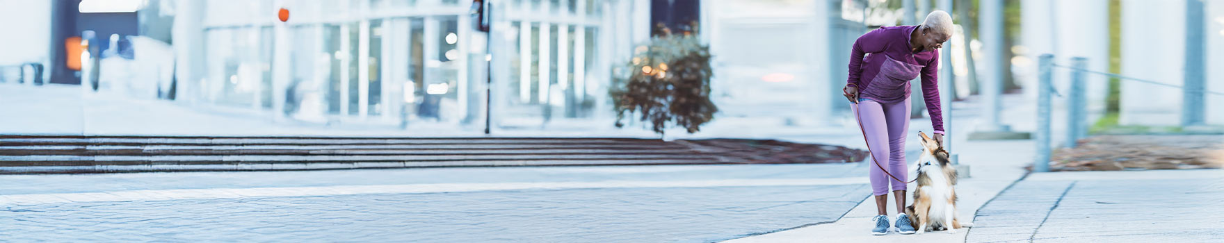 A woman leaning down to pet her dog