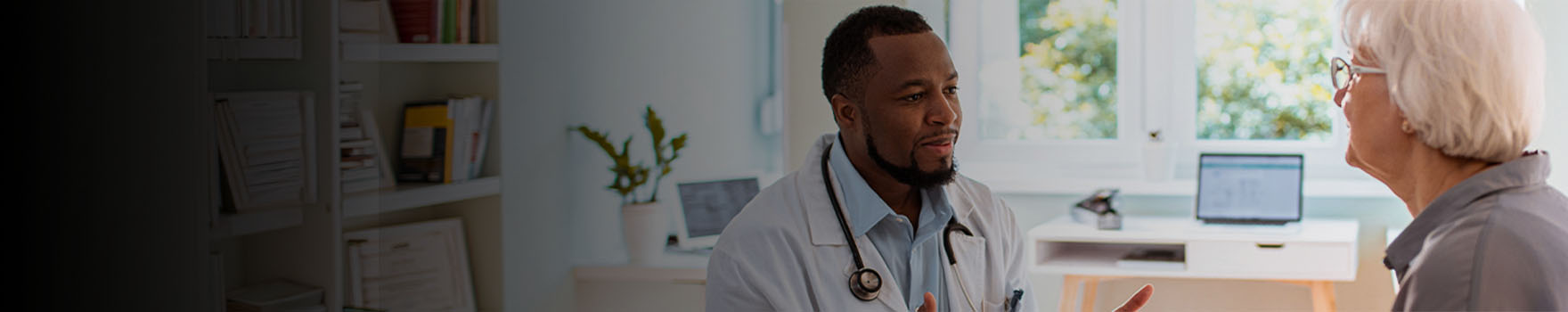 male doctor talking to elderly female patient in his office