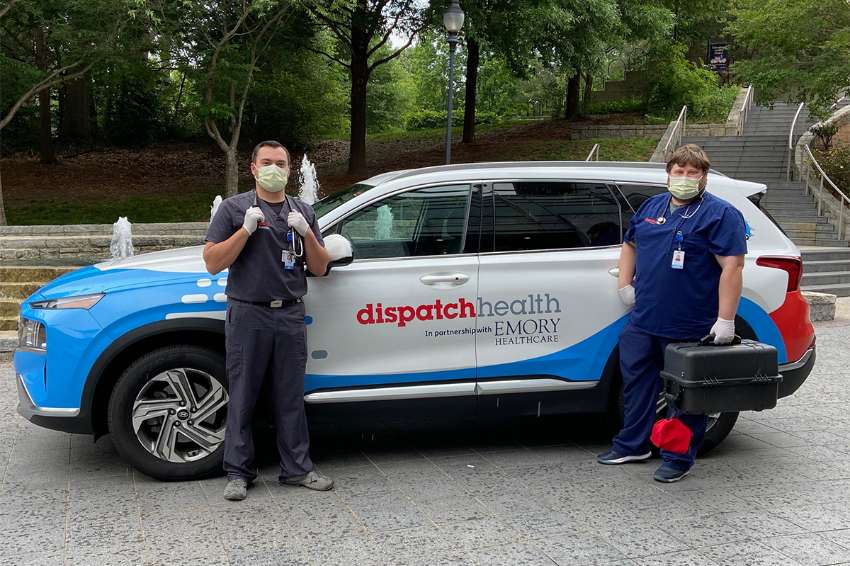 medical professionals with equipment stand in front of a dispatch health vehicle