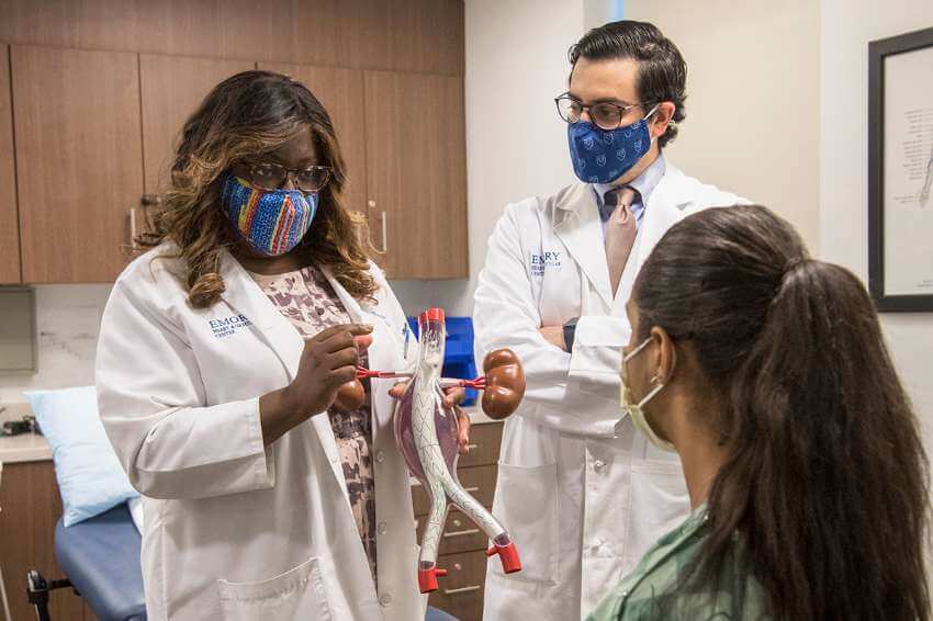 Olamide Alabi, MD gives a demonstration to a patient with a model version of internal organs