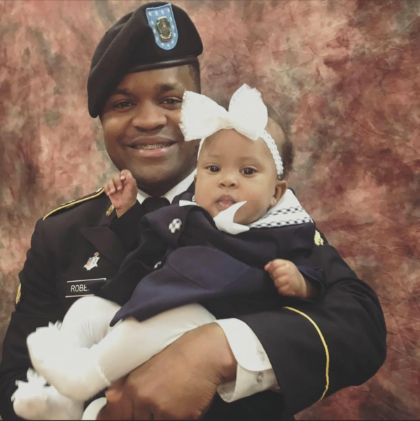 Roberts in his Army uniform holding his baby daughter Mylan