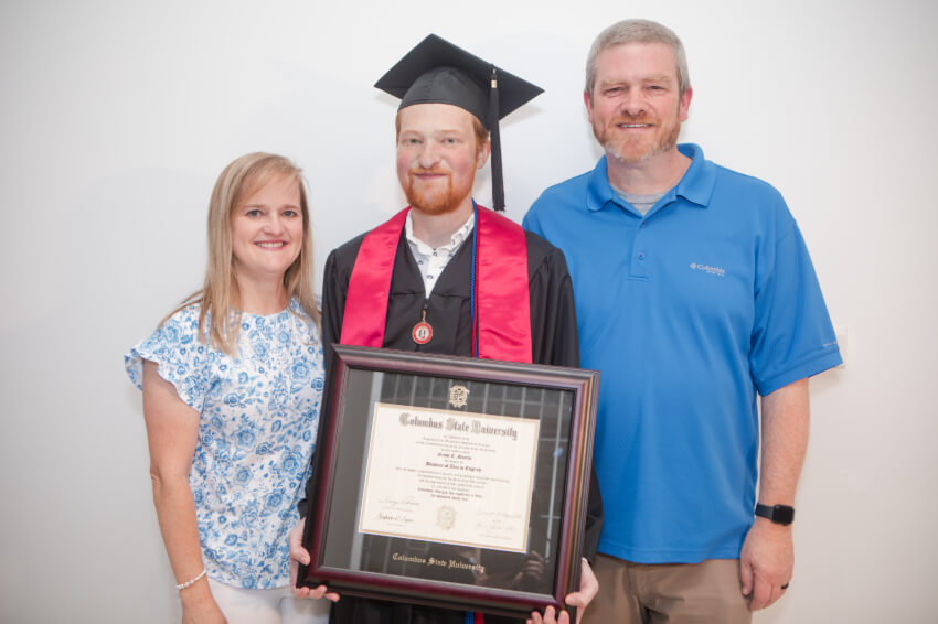 Grant poses with his diploma and his parents