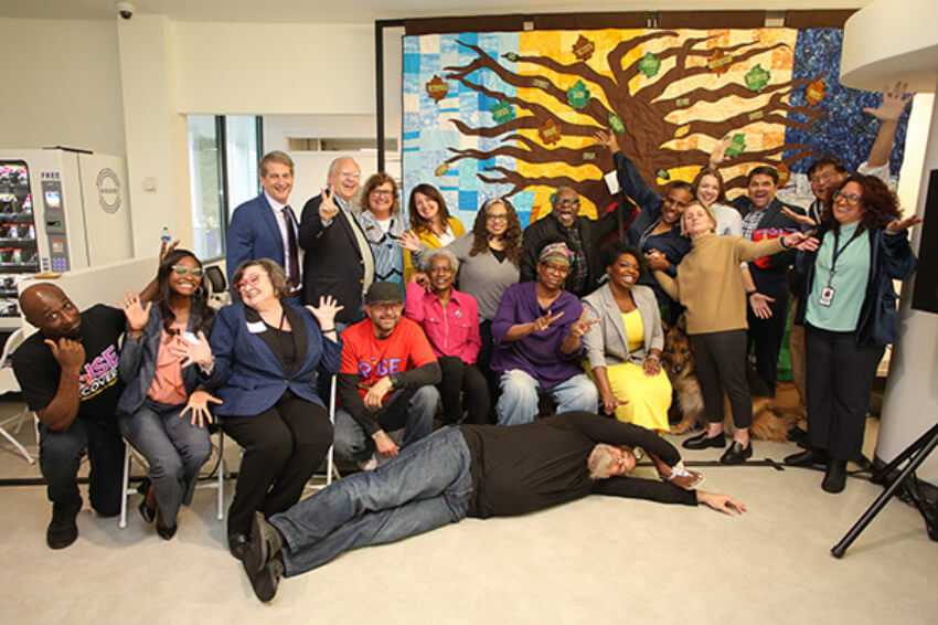 group does silly poses in front of the quilt at AAG