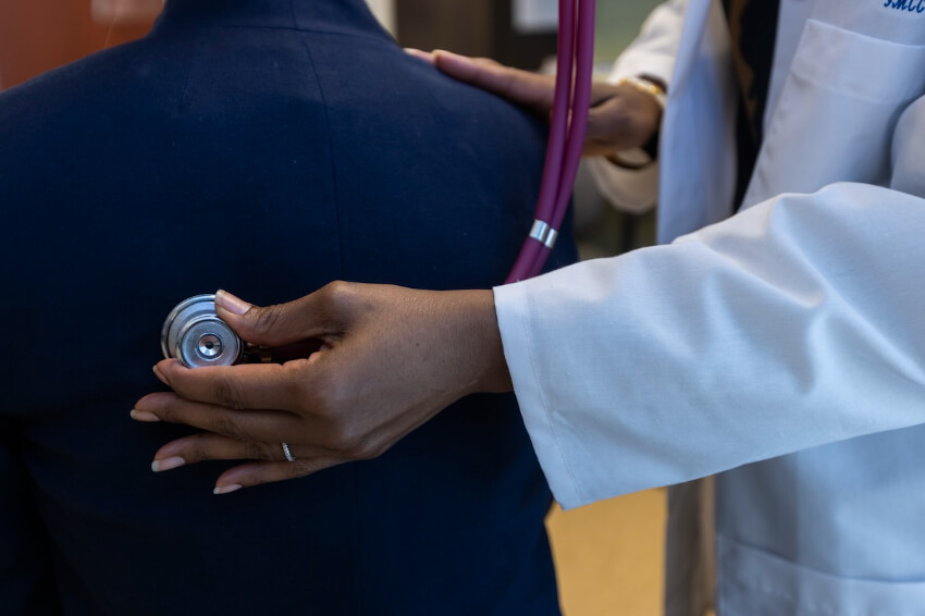 Photo of person putting stethoscope on patient's back