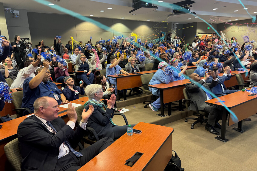 a lecture room full of Emory employees clapping and cheering with confetti streamers in the air