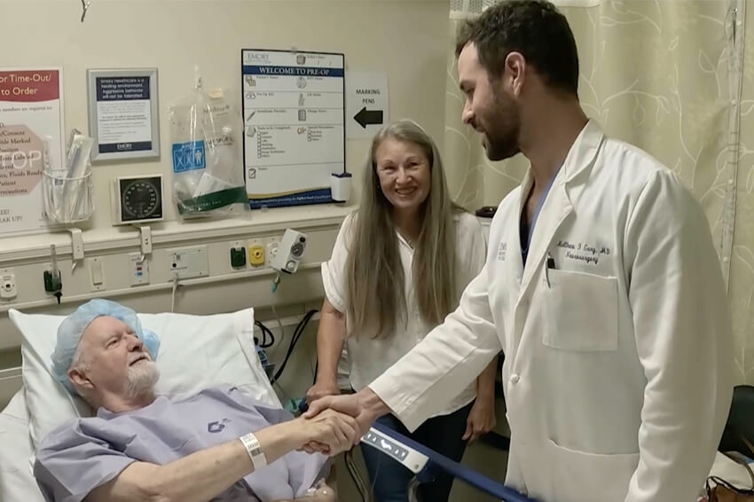 male patient in hospital bed shaking health provider's hand