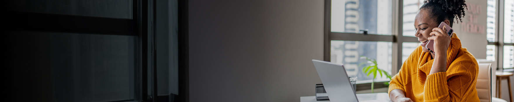 woman talking on her phone while sitting in front of her laptop