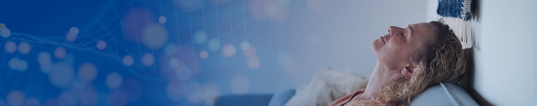 A woman relaxes on a couch, her head gently supported by a plush pillow.