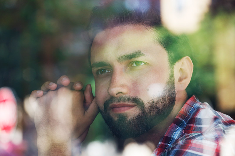 A man quietly looks through the window, his mind absorbed in thought.