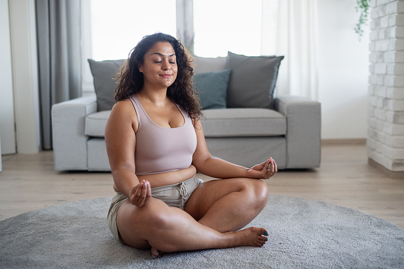 Woman doing yoga and unwinding in her living room.